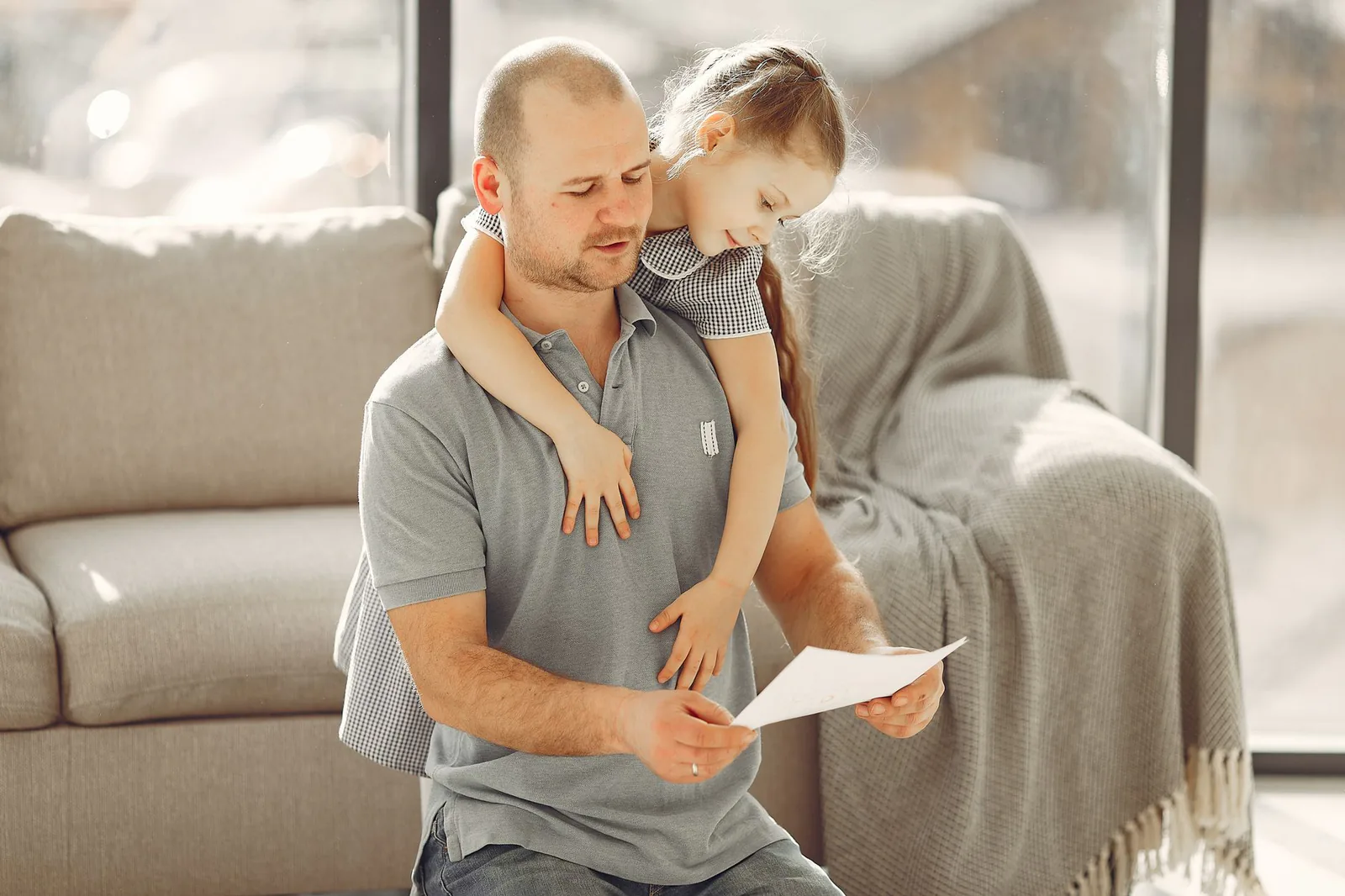 A father and daughter hugging happily while reading a letter together at home